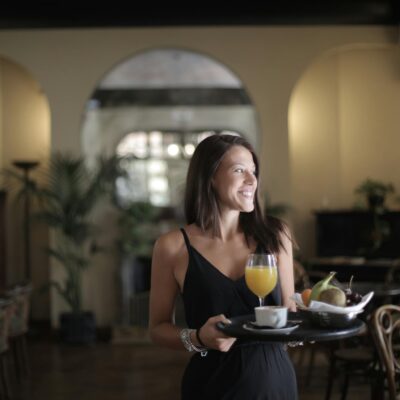 Happy woman carrying tray with breakfast in hotel restaurant